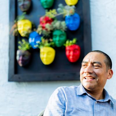 Person smiling next to a colorful mask wall display.