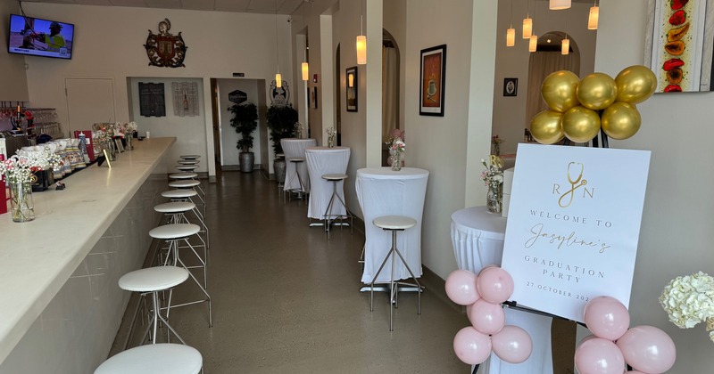A room decorated for a graduation party, with a bar and high-top tables