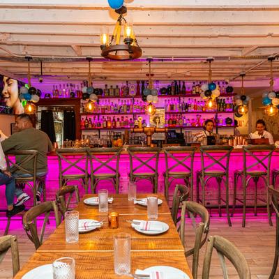 Interior, seating area with set tables, guests and staff at the bar in the background.