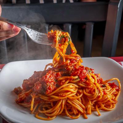 A hand is shown twirling a forkful of spaghetti marinara.