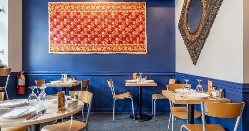 Interior, dining area with blue wall, big mirror and decorative tapestry on the wall
