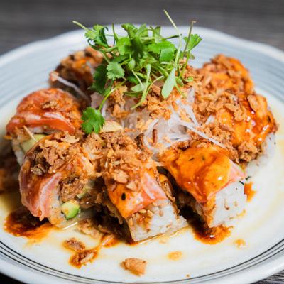 Filled rice rolls topped with slices of salmon, a spicy sauce and crispy fried onions.
