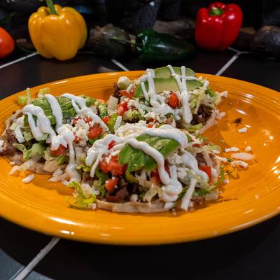 Mexican tostadas with avocado, tomatoes, cheese, and sour cream.