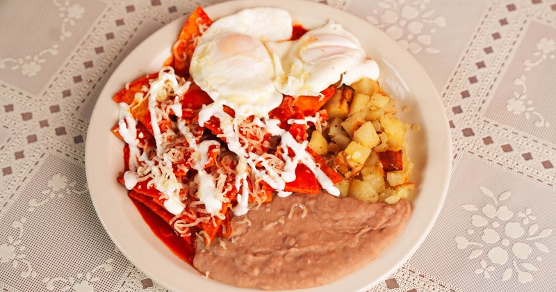 Red chilaquiles with poached eggs, refried beans, and seasoned potatoes