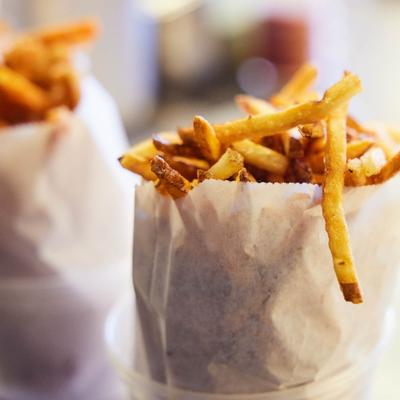 Two servings of French fries in paper bags.