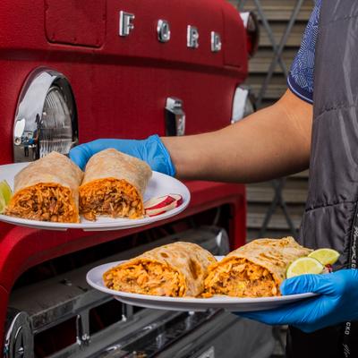 Server holding two plates with burritos.