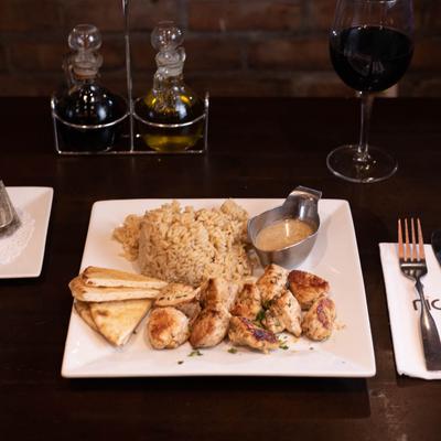 Chicken souvlaki with pita tips , rice and sauce.