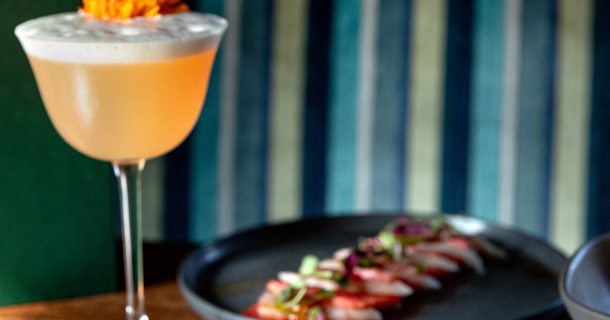 Cocktail beside plated appetizers on a wooden table