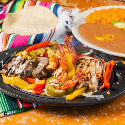 Steak, chicken, and shrimp fajitas, with onions, peppers, sour cream, pico de gallo, and guacamole.