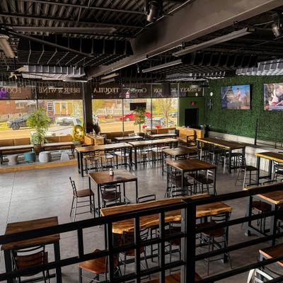 Interior, modern industrial design with wooden tables and stools, large windows.