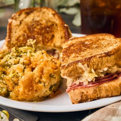 Reuben Sandwich topped with sauerkraut, served with a side of vegetable casserole.