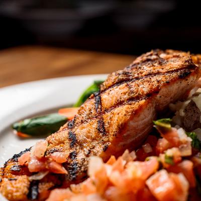 Grilled Salmon  served atop chopped tomatoes, onions, capers.
