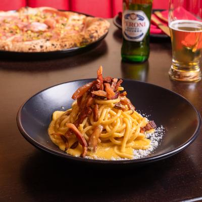 Bigoli pasta with cured meat, egg yolk, and cheese.