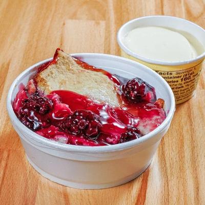 Blackberry Cobbler served with a cup of vanilla ice cream on a wooden table.