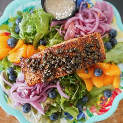 Mixed greens salad with blueberries, pickled onions, tangerines, and salmon topped with capers.