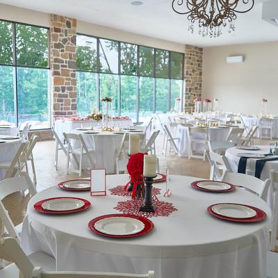 Wedding reception room with white tables and place settings.