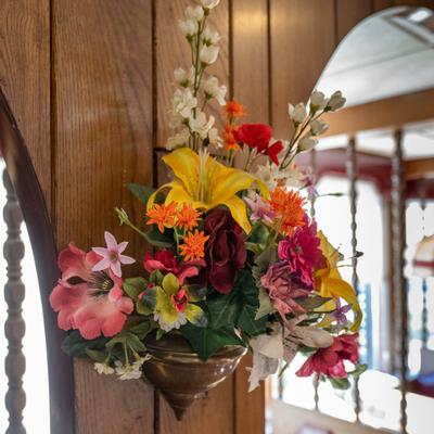 Colorful artificial flower arrangement on a wooden wall panel.