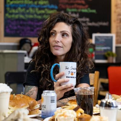 Person seated holding a coffee mug.