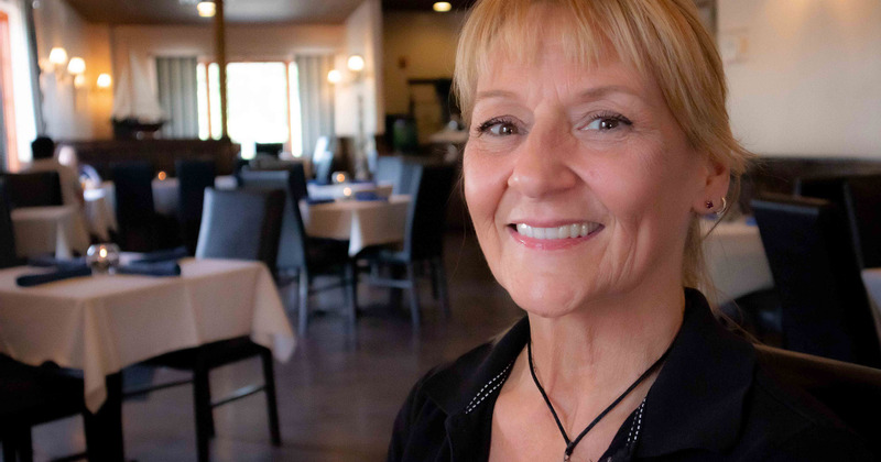 Lady staff member, tables ready for guests in the back