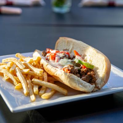 Steak sandwich, with sauteed onions and peppers, melted cheese, mayo, and a side of fries.