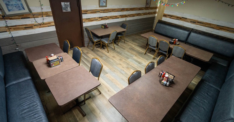 Interior - wooden floors, brown tables, padded bench seating, colorful string lights on the ceiling