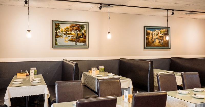 Interior of cozy dining area with upholstered dining booths and tables set for guests