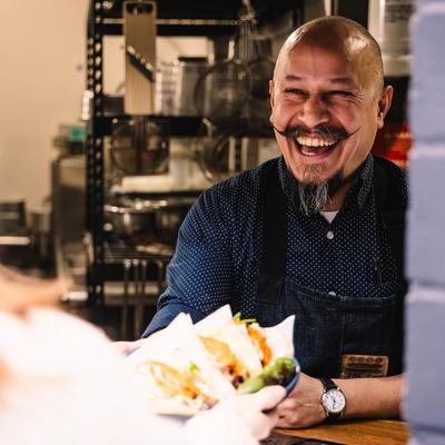 Kitchen window, an employee serves an order to a customer.