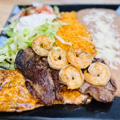 Carne asada and shrimp plate served with rice, refried beans, lettuce, and sour creme.