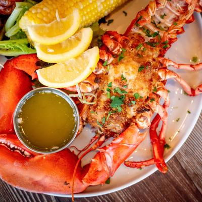Stuffed lobster with melted butter, lime wedges, and corn on the cob.
