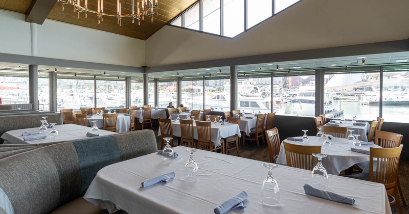 Restaurant interior with table settings and a view of a marina