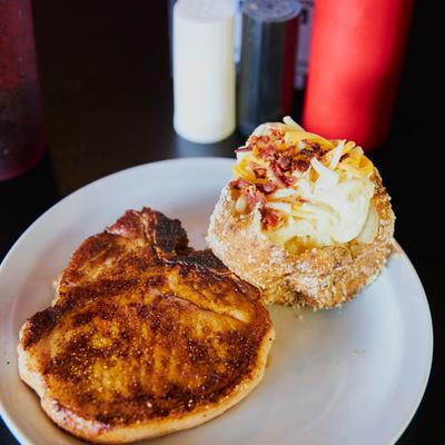 Grilled pork chop, with a loaded baked potato.