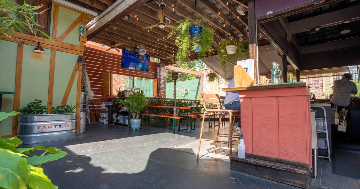 Covered patio with picnic tables, hanging plants, and a service counter