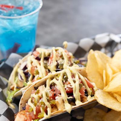 Tequila Lime Chicken Tacos with chips, accompanied with a blue cocktail.