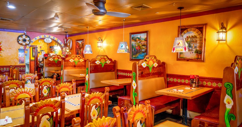 Interior, open space dining area, booths with tables, tables with carved wooden chairs