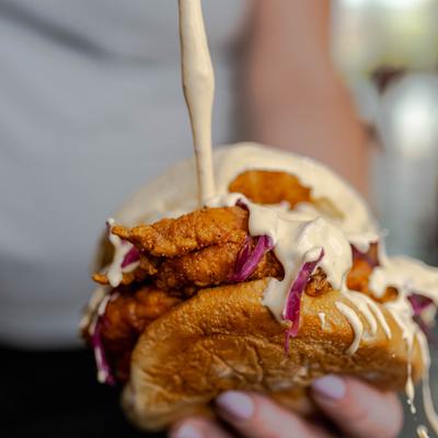 Adding sauce to fried chicken sandwich, close up.