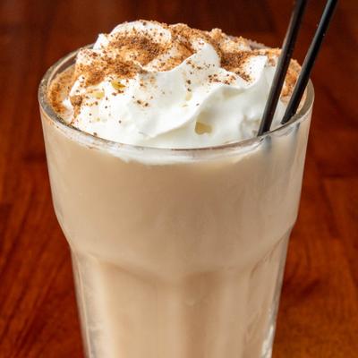 Close up of milkshake topped with whipped cream in a glass.