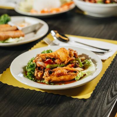 A plate of Hello Vietnam's Wings sits on a table with various other dishes.