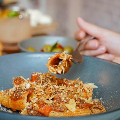 Rigatoni Bolognese, a customer holding some with a fork.