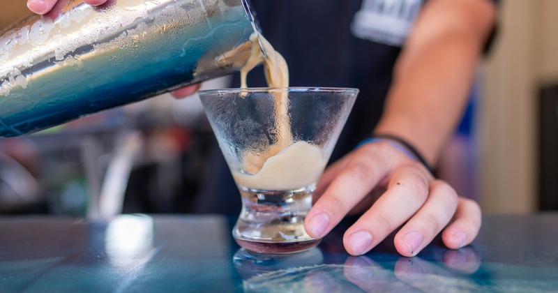 Cocktail being strained from the shaker into a martini glass