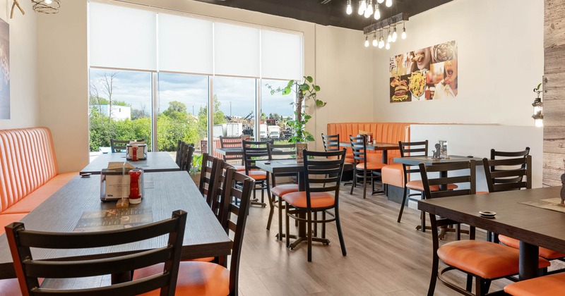 Interior, tables and chairs in dining area with large windows