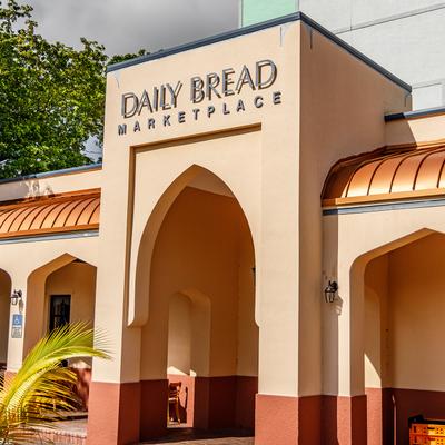 Angled view of a storefront with signage and arches on a sunny day.