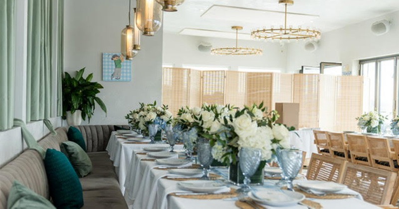Elegant dining table set with white flowers and blue glassware in a bright room