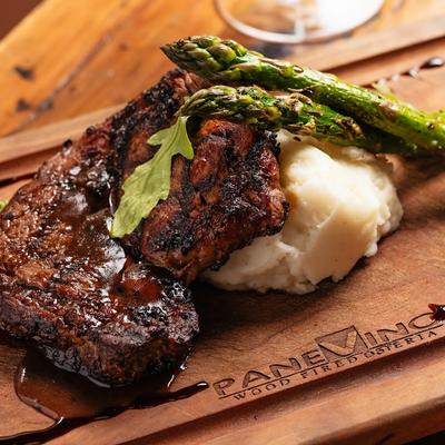 Grilled steak with mashed potatoes and asparagus on a branded wooden board.