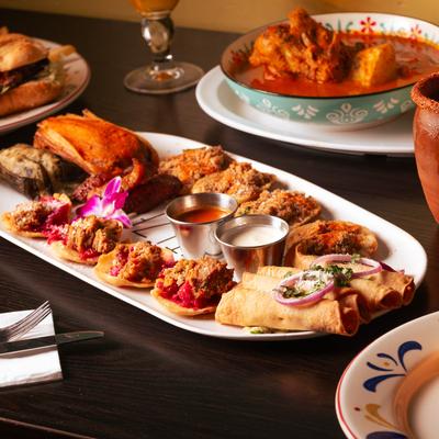 A platter of various appetizers, sits beside a rustic clay mug cocktail.