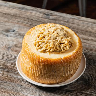 Spaghetti tossed with pecorino cheese, ground black pepper, and butter, served in pecorino cheese wheel.