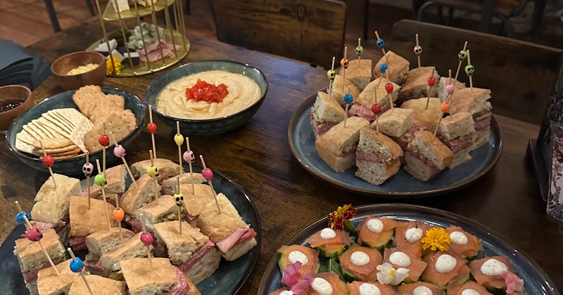 A buffet table with sandwich trays and charcuterie