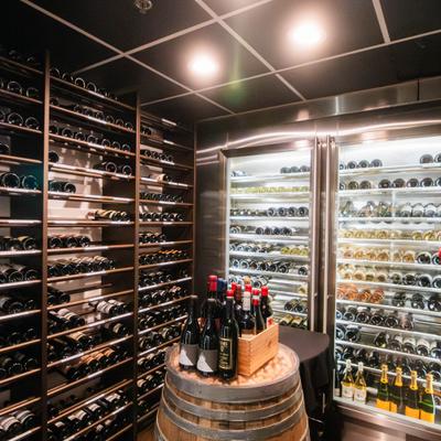 Wine cellar with shelves, glass refrigerators, and barrel display.