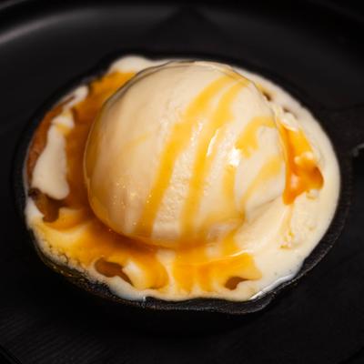 A chocolate chip cookie bowl filled with vanilla ice cream and caramel sauce.