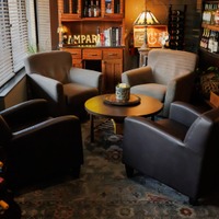 Warm and intimate lounge area with upholstered armchairs arranged around a small round table.