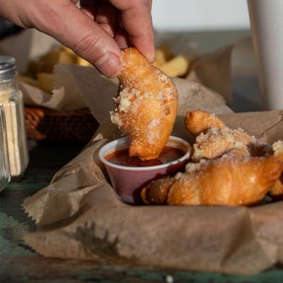 A hand dipping a garlic knot into marinara sauce.
